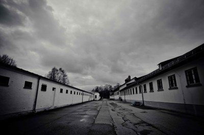 Grauer Himmel, perspektivischer Blick zweier Gebäude, Links ehemaliger Bunker, das ehemalige Lagergefängnis des KZ Dachau